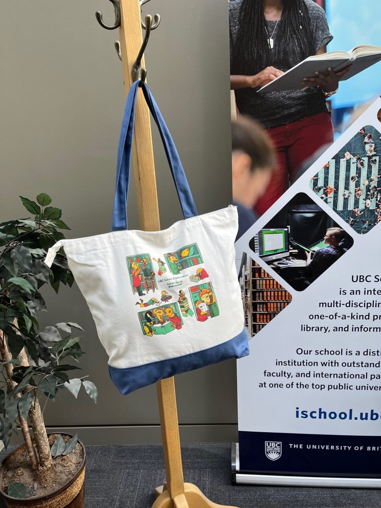 UBC School of Information tote bag hanging on a coat rack at the entrance of the iSchool.