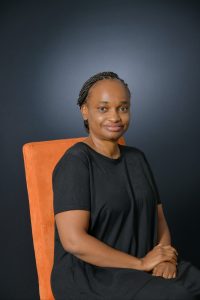 Nampombe Saurombe poses for the photo while sitting down in an orange chair.